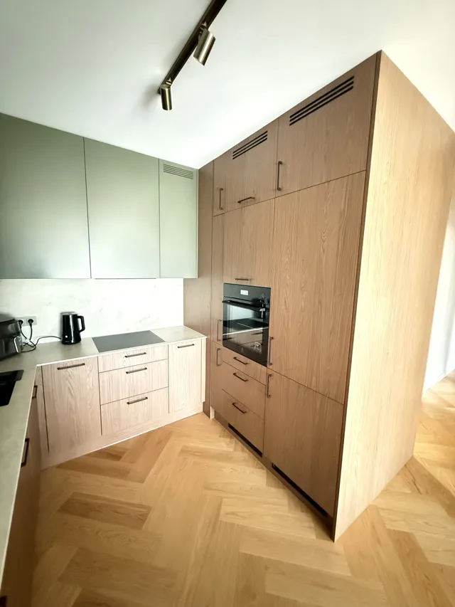 Kuchnia z zielonymi szafkami, drewnianą zabudową i jasnym blatem